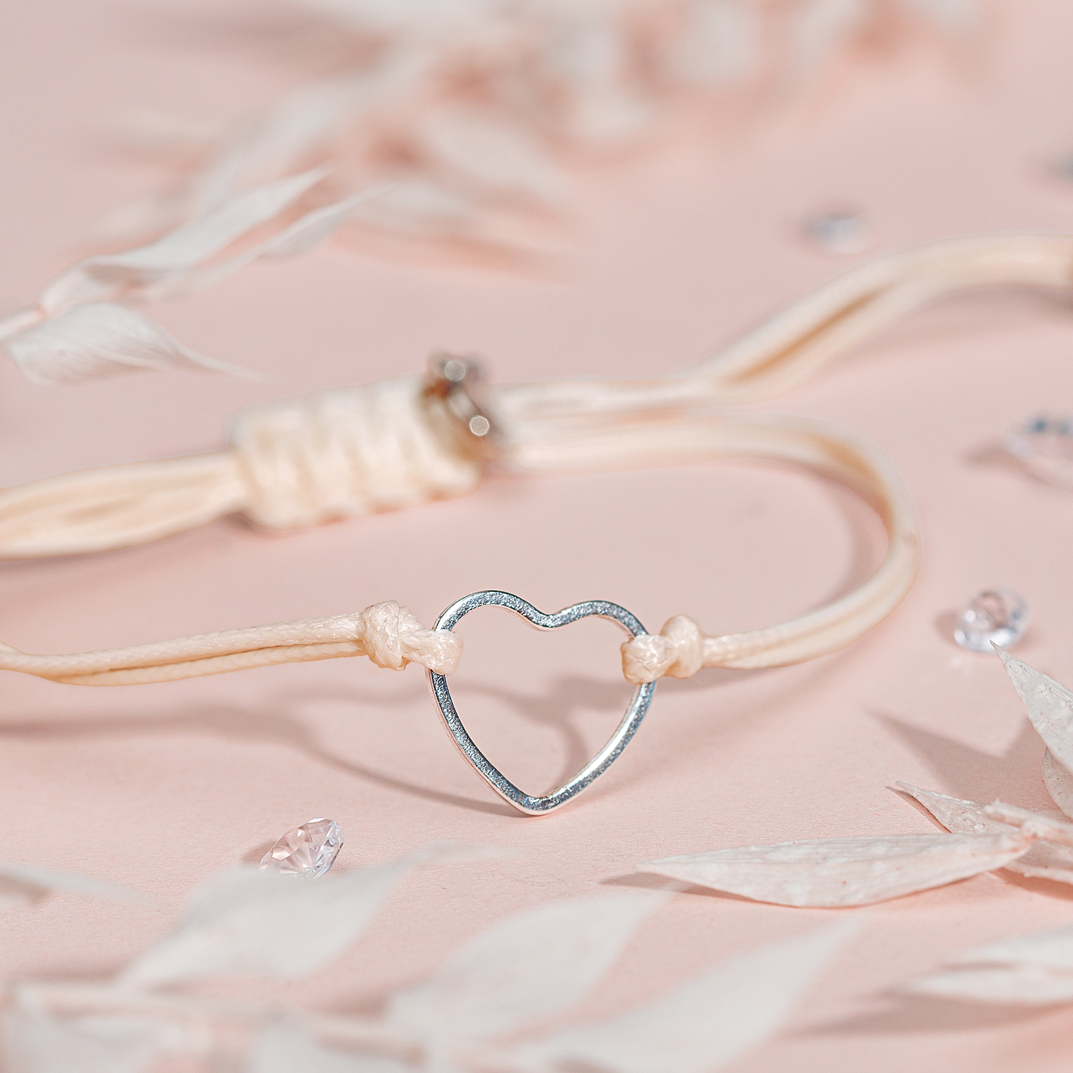 Stackable heart bracelet for women on a pale pink background