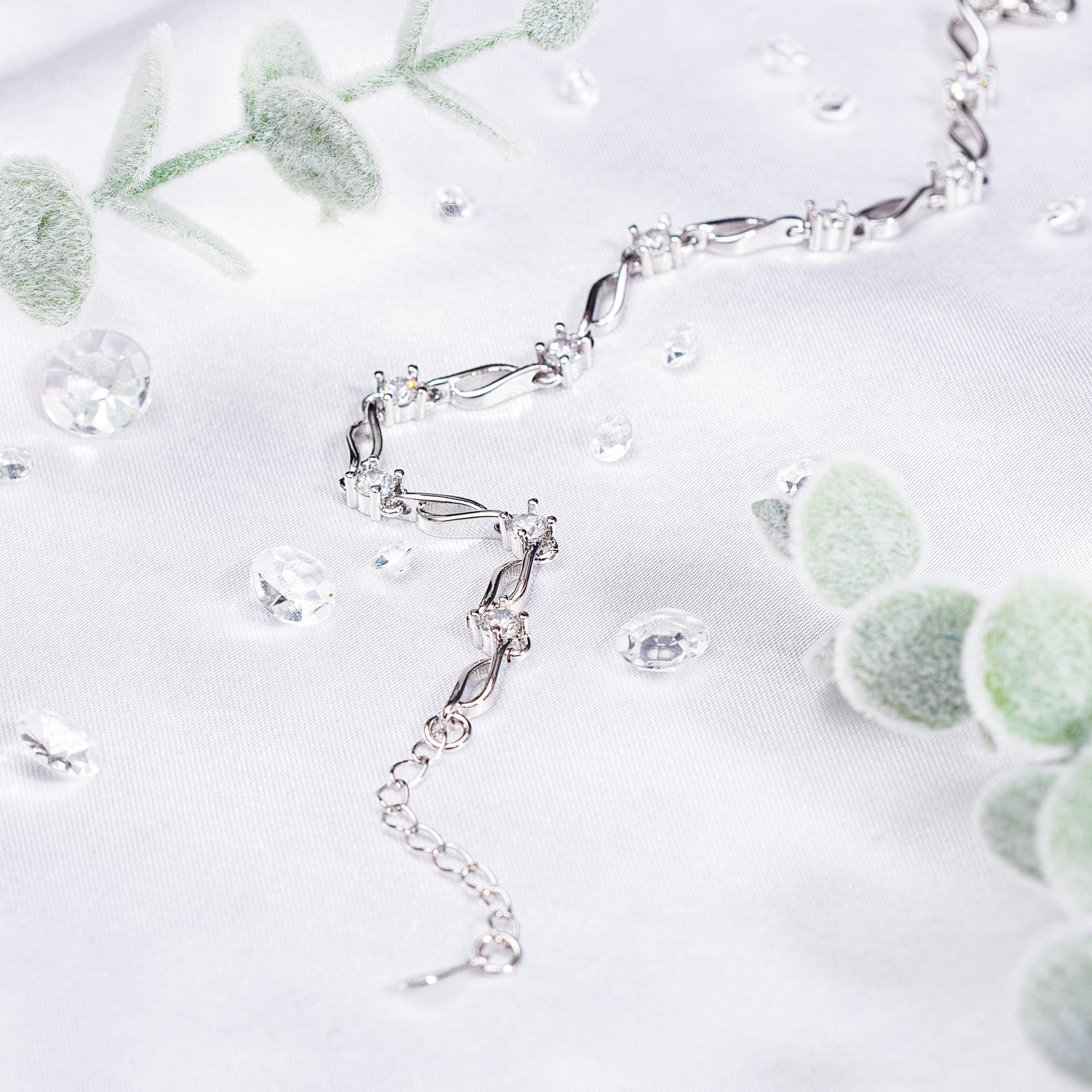 silver plated bracelet on a white background with gems and eucalyptus stems