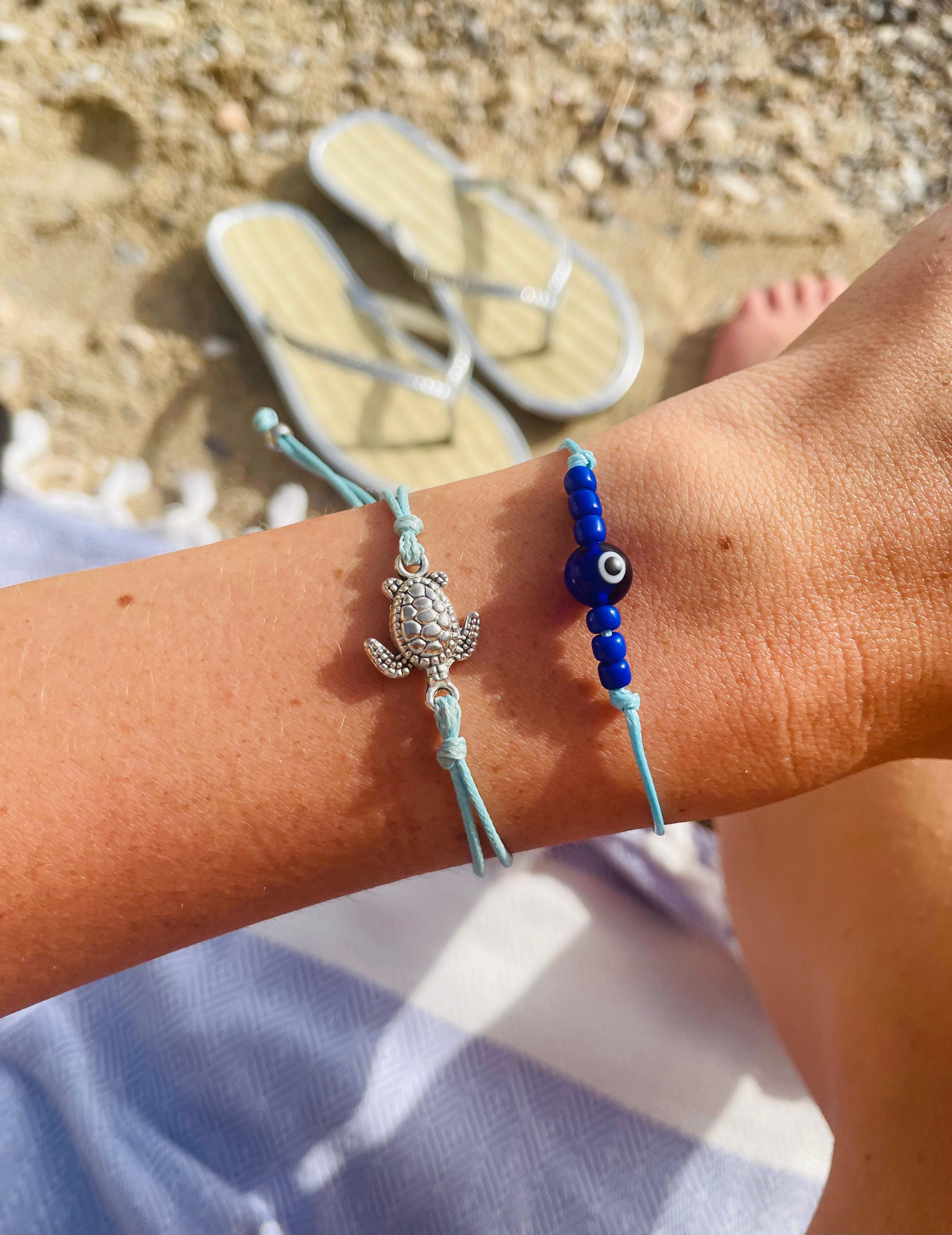 a woman's arm with a summer bracelet stack as the focal point. Including a cute tiny turtle bracelet and an affordable evil eye bracelet