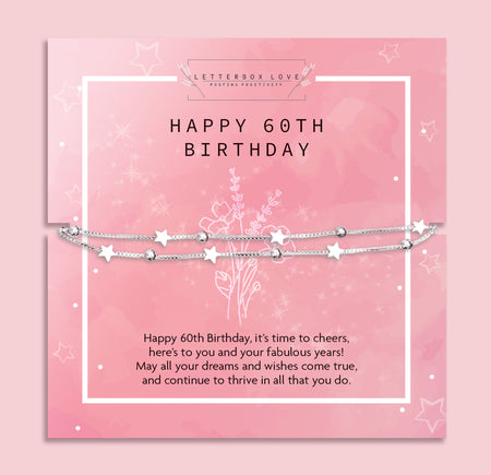 A celebratory 60th birthday bracelet by Letterbox Love, displayed on a soft pink background with glistening white flowers. The bracelet features a silver chain interspersed with shimmering stars and beads, conveying elegance and joy. It lies atop a matching pink birthday card that reads
