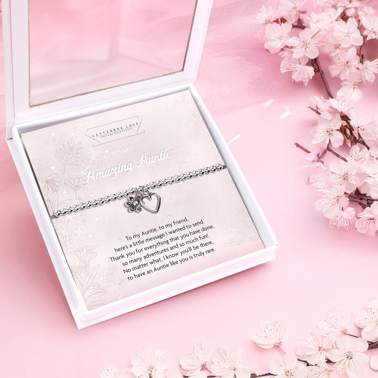 Silver beaded bracelet with heart and flower charms, displayed in a white gift box alongside a card titled