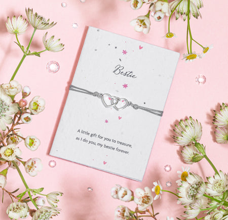 A silver heart charm bracelet displayed on a seed paper card labeled