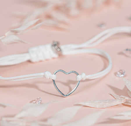 A white cord friendship bracelet with a silver-plated hollow heart charm making an affordable gift for mum