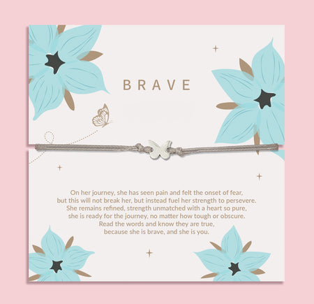 Silver bracelet with a butterfly charm presented on a white 'BRAVE' card decorated with teal flowers and a touching message about strength and perseverance.