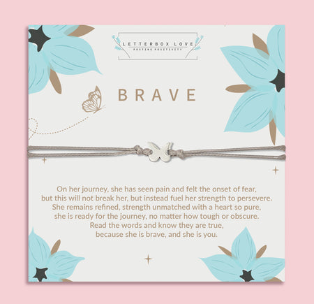 Silver bracelet with a butterfly charm presented on a white 'BRAVE' card decorated with teal flowers and a touching message about strength and perseverance.