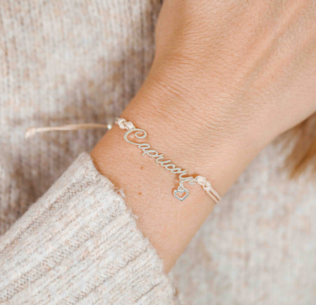 A woman wearing a dainty bracelet with the word “Capricorn” and a tiny heart charm, a meaningful zodiac-inspired gift for her.