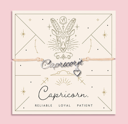 Adjustable peach cord bracelet with a silver 'Capricorn' charm and heart pendant, displayed on a zodiac-themed card featuring a goat illustration and traits reading