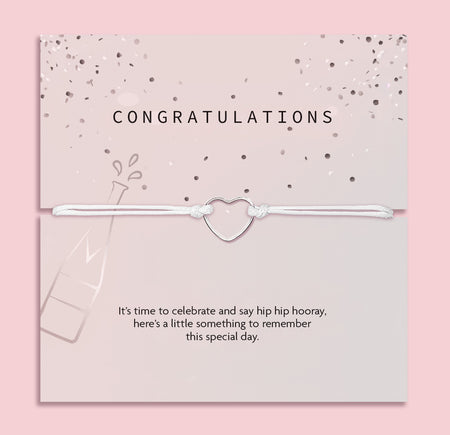 Letterbox Love 'Congratulations' bracelet – delicate silver heart charm on a white cord, presented on a pink confetti card with a champagne bottle design and celebratory message. A thoughtful letterbox gift for graduation, new job, engagement or promotion. Affordable jewellery gift to mark a special milestone for her.