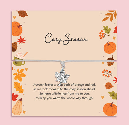 Cosy Season autumn bracelet featuring a silver maple leaf charm on an adjustable cord, presented on a seasonal card with pumpkins, leaves, and cosy illustrations. Perfect autumn jewellery gift, fall accessory, or thoughtful present for birthdays, Thanksgiving, or seasonal celebrations. Our bracelet is ready to gift and captures the warmth of autumn, making it an ideal keepsake for lovers of fall fashion and meaningful jewellery.