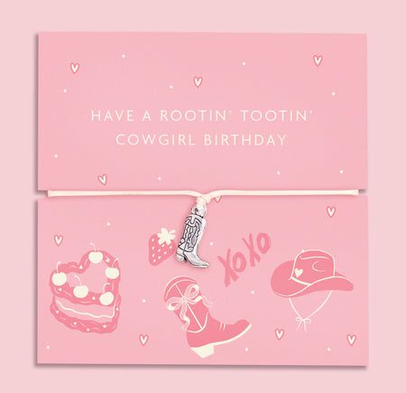 A pink adjustable bracelet featuring a silver-plated cowboy boot charm, displayed on a playful pink backing card with the message