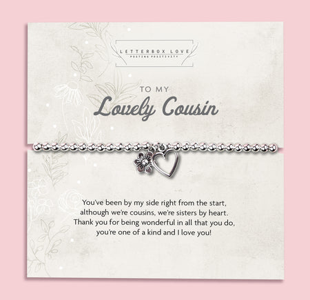 A silver beaded bracelet with a heart and flower charm displayed on a card reading