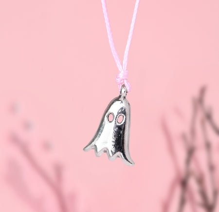 Silver ghost-shaped charm bracelet on a pink cord against a pink background. Cute Autumn jewellery for women for halloween and fall