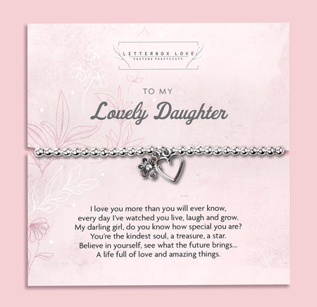 A silver beaded bracelet with a heart and flower charm displayed on a card reading