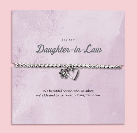 A silver-plated beaded bracelet with a heart and flower charm displayed in a premium white keepsake box. The backing card inside is soft pink with the title
