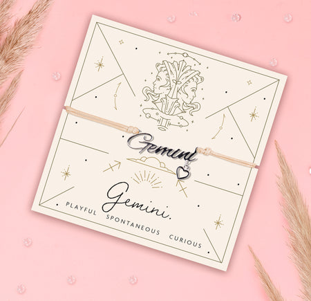 Bracelet with 'Gemini' charm on a branded card with astrological design on a pink background. Zodiac bracelet under £20.
