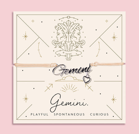 Adjustable peach cord bracelet with a silver 'Gemini' charm and heart pendant, displayed on a zodiac-themed card with a twin illustration and the traits
