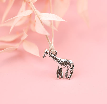 A cute silver-plated giraffe charm on a beige string friendship bracelet, with a pale pink background.