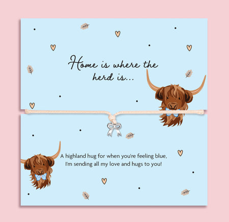 Highland cow bow charm bracelet on illustrated card with two cute Highland cows and the words “Home is where the herd is”, presented as a sentimental gift to cheer someone up.