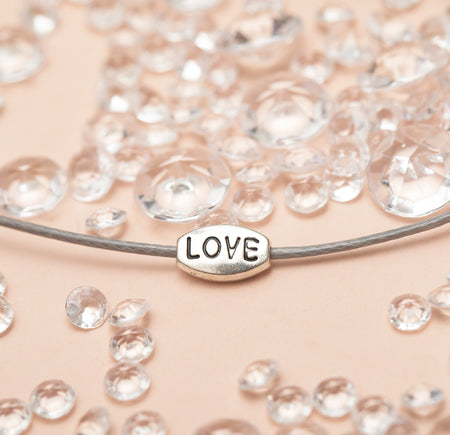 grey chord with love charm on a pale pink background