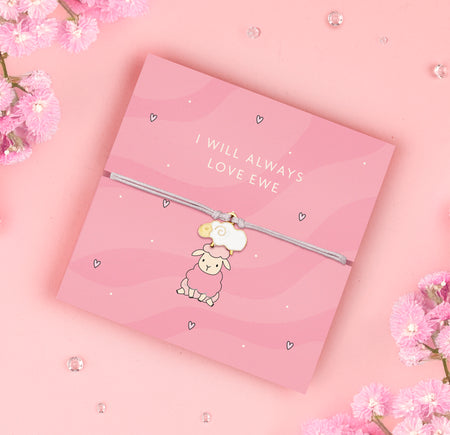 A pink adjustable bracelet featuring an adorable enamel sheep charm, displayed on a pastel pink backing card with the message