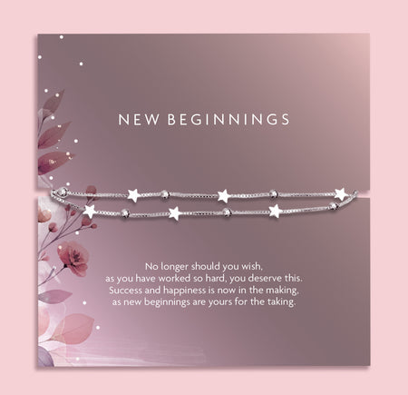 Flat lay of a “New Beginnings” bracelet gift by Letterbox Love, featuring a double silver box chain with star and bead charms, displayed on a mauve-toned sentiment card with floral illustrations and an inspiring message.