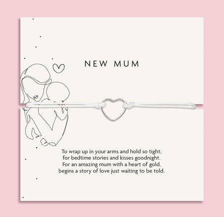 An elegant 'New Mum' bracelet with a dainty heart charm, displayed on a pastel pink background adorned with baby's breath flowers and sparkling crystals, symbolizing the gentle embrace of motherhood.