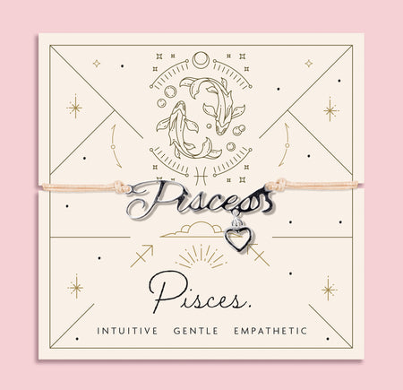 Adjustable peach cord bracelet with a silver 'Pisces' charm and small heart pendant, displayed on a zodiac-themed backing card with a fish illustration and traits reading