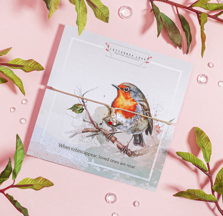 Adjustable bracelet with a silver and red enamel robin charm, displayed on a watercolour-style card featuring a robin on a branch. The card includes the phrase 'When robins appear, loved ones are near'. A thoughtful sympathy or remembrance gift from Letterbox Love.