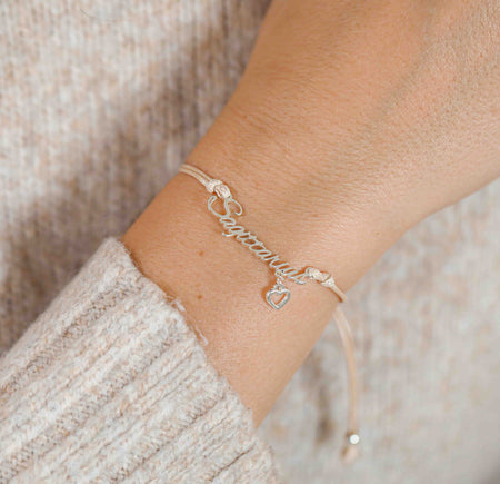 A woman wearing a dainty bracelet with the word “Sagittarius” and a tiny heart charm, a lovely zodiac-themed gift for her.