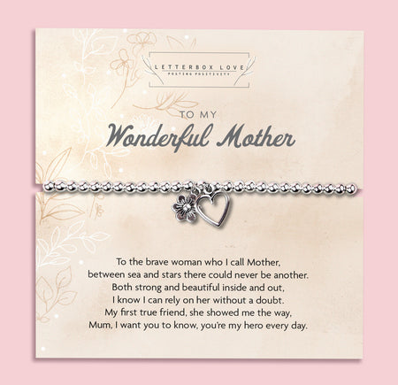 A silver beaded bracelet with a heart and flower charm displayed on a card reading