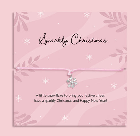 Delicate silver snowflake charm bracelet on a pink cord, displayed on a pink “Sparkly Christmas” poem card with festive snowflake design, thoughtful Christmas gift for her by Letterbox Love.