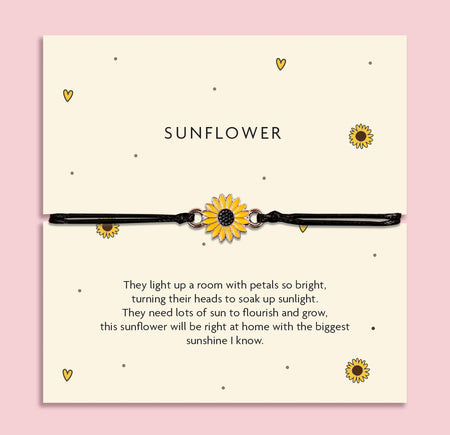 Adjustable black cord bracelet with a yellow sunflower charm, displayed on a cream card titled 'Sunflower'. The card features a cheerful poem about brightness, growth, and sunshine. Surrounded by flowers on a pink background, this is a joyful gift from Letterbox Love.