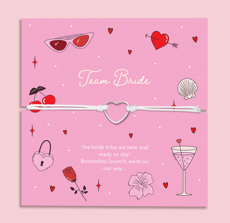 Team Bride hen party bracelet – cute silver heart charm on white cord, displayed on a fun pink card with cocktail, cherry, and love heart designs. Perfect for bridesmaid proposal boxes, hen do favours, bride tribe accessories, or bottomless brunch party gifts. Affordable letterbox jewellery for bachelorette celebrations.