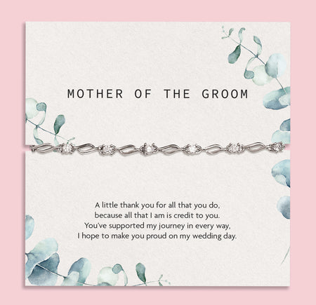 Elegant 'Mother of the Groom' card set against a silky white fabric backdrop. The card, adorned with soft blue floral designs, expresses gratitude and appreciation with a heartfelt message. Draped over the card is a sophisticated silver bracelet with intricate detailing.
