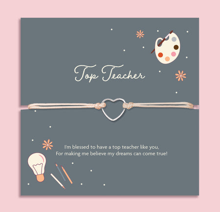 Cream adjustable cord bracelet with a silver open heart charm, displayed on a navy blue card with the message 'Top Teacher'. The card features illustrations of a paint palette, lightbulb, and pencils, with a thank you note for inspiring dreams. A thoughtful teacher appreciation gift from Letterbox Love.
