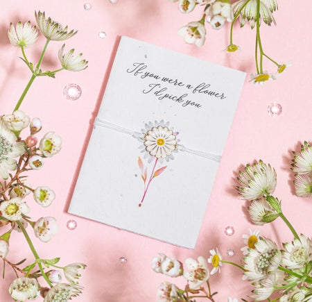 A white daisy charm bracelet presented on a seeded greeting card with the message
