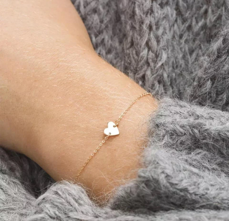 a woman's wrist with an elegant gold heart bracelet. Jewellery to help anxiety and stress