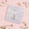 Elegant 'Angels' card on a soft pink background, decorated with subtle feather illustrations and the comforting quote, 'When feathers appear, angels are near.' Paired with the card is a delicate bracelet featuring a detailed angel wing charm.