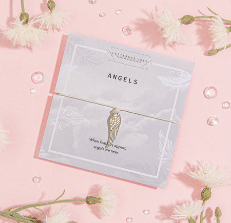 Elegant 'Angels' card on a soft pink background, decorated with subtle feather illustrations and the comforting quote, 'When feathers appear, angels are near.' Paired with the card is a delicate bracelet featuring a detailed angel wing charm. 
