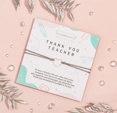 Appreciative 'Thank You Teacher' card on a soft pink background, adorned with geometric and school-related illustrations. The card features heartfelt gratitude text and is accompanied by a delicate bracelet with a heart charm.