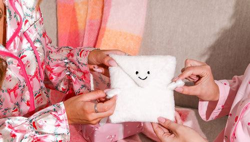 A christmas scene with two women holding the 'hugsy' plush gift wrap