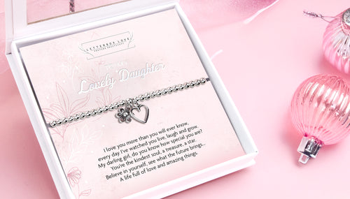 A pink, festive set-up with a Letterbox Love Gift box featuring a silver beaded bracelet. The bracelet is silver-plated with a heart and small flower charm. It has a sentimental message titled "To my lovely daughter"