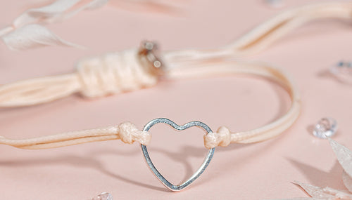 Stackable heart bracelet for women on a pale pink background
