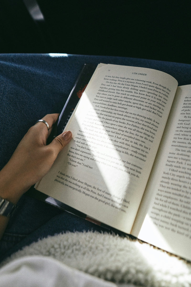 a woman in a shaded area reading an open book