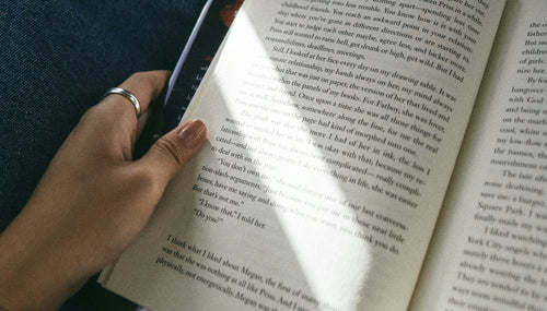 a woman in a shaded area reading an open book