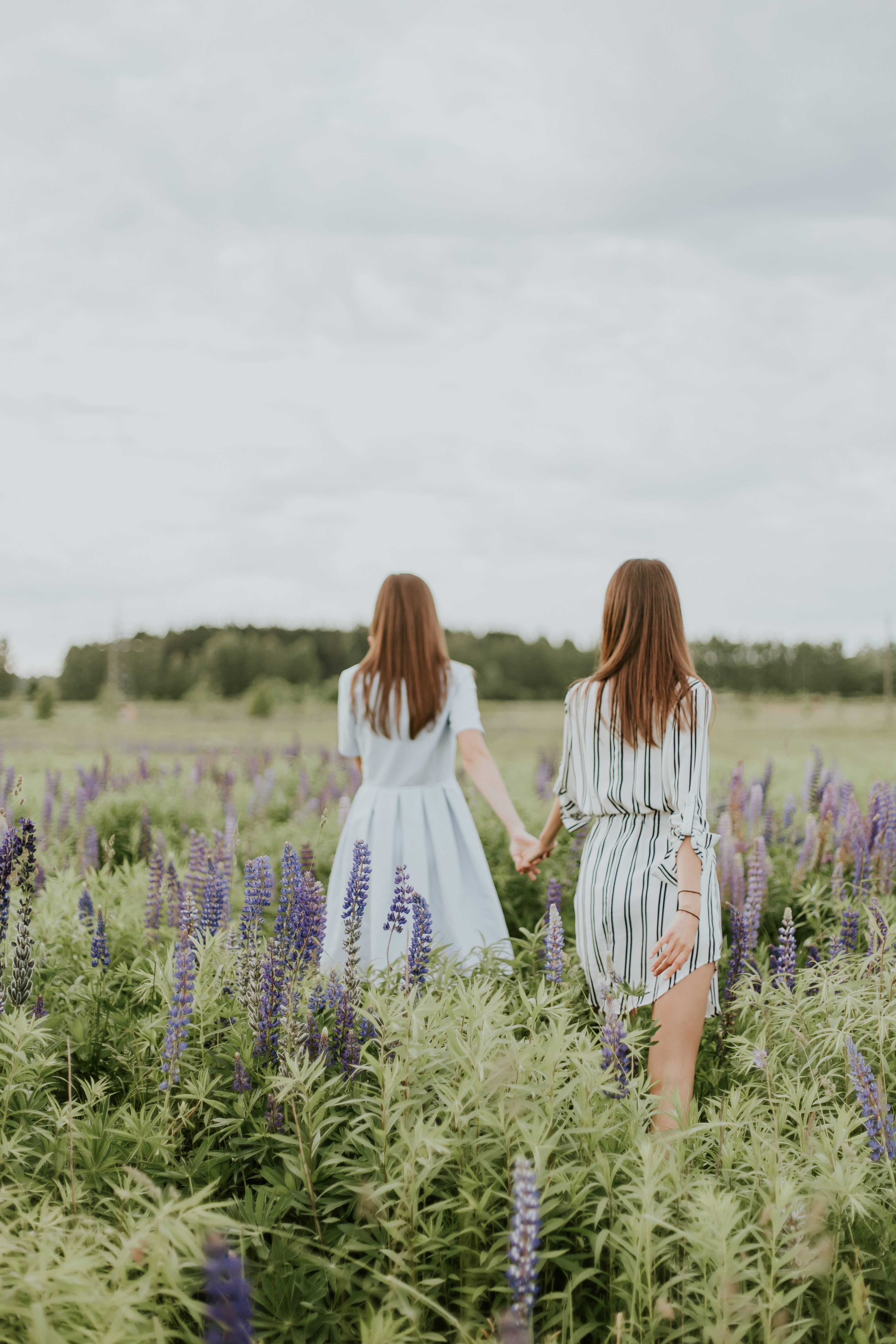 two women with bracelets walking through a lavender field