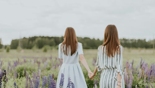 two women with bracelets walking through a lavender field