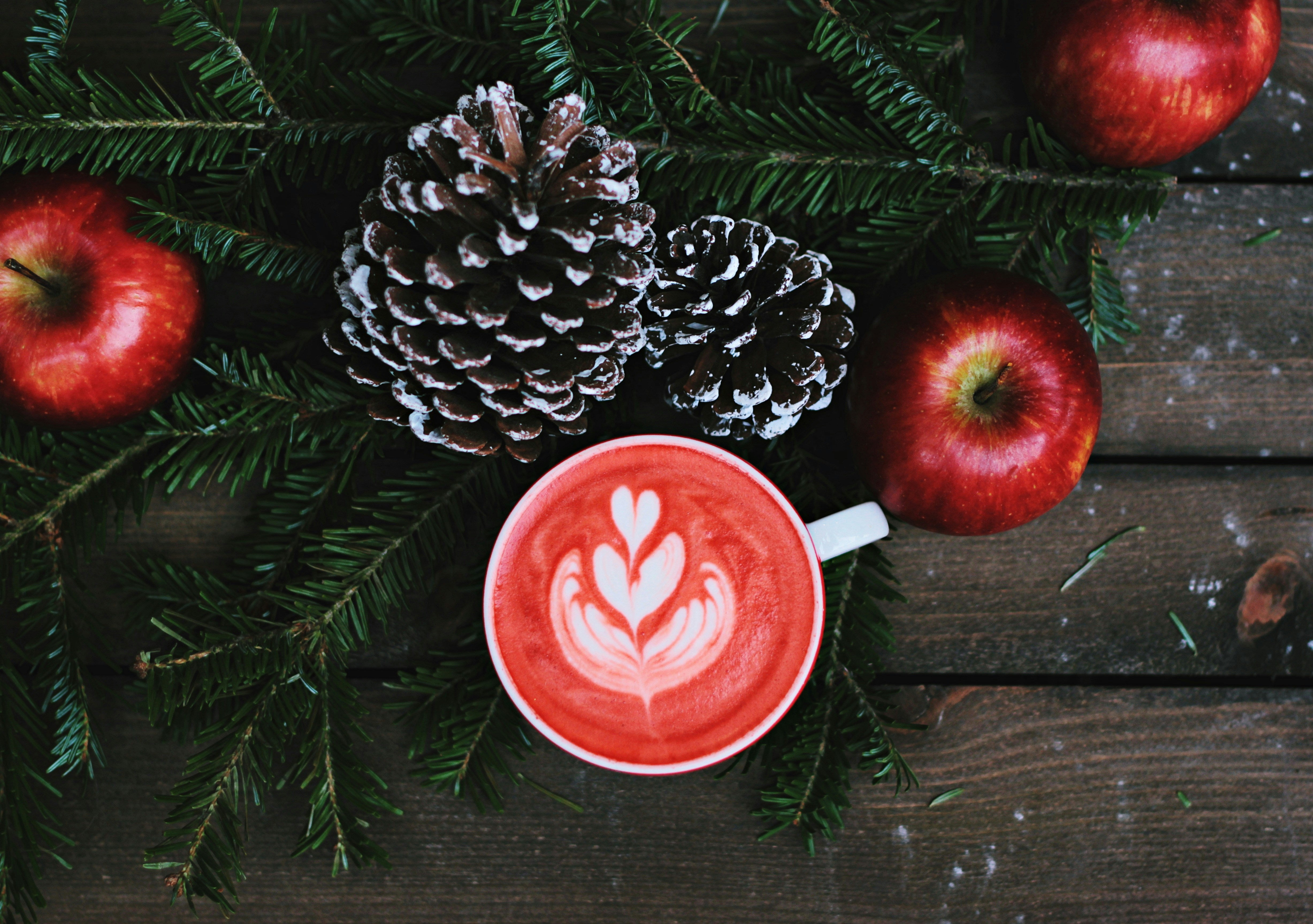 a wooden backdrop with christmas sprigs, pine cones and an aesthetic latte