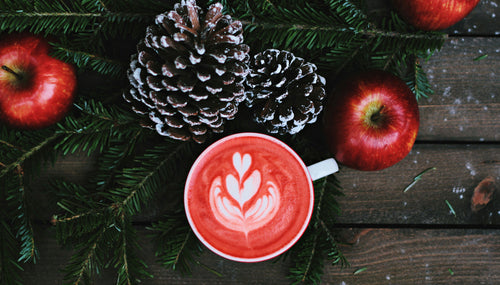 a wooden backdrop with christmas sprigs, pine cones and an aesthetic latte