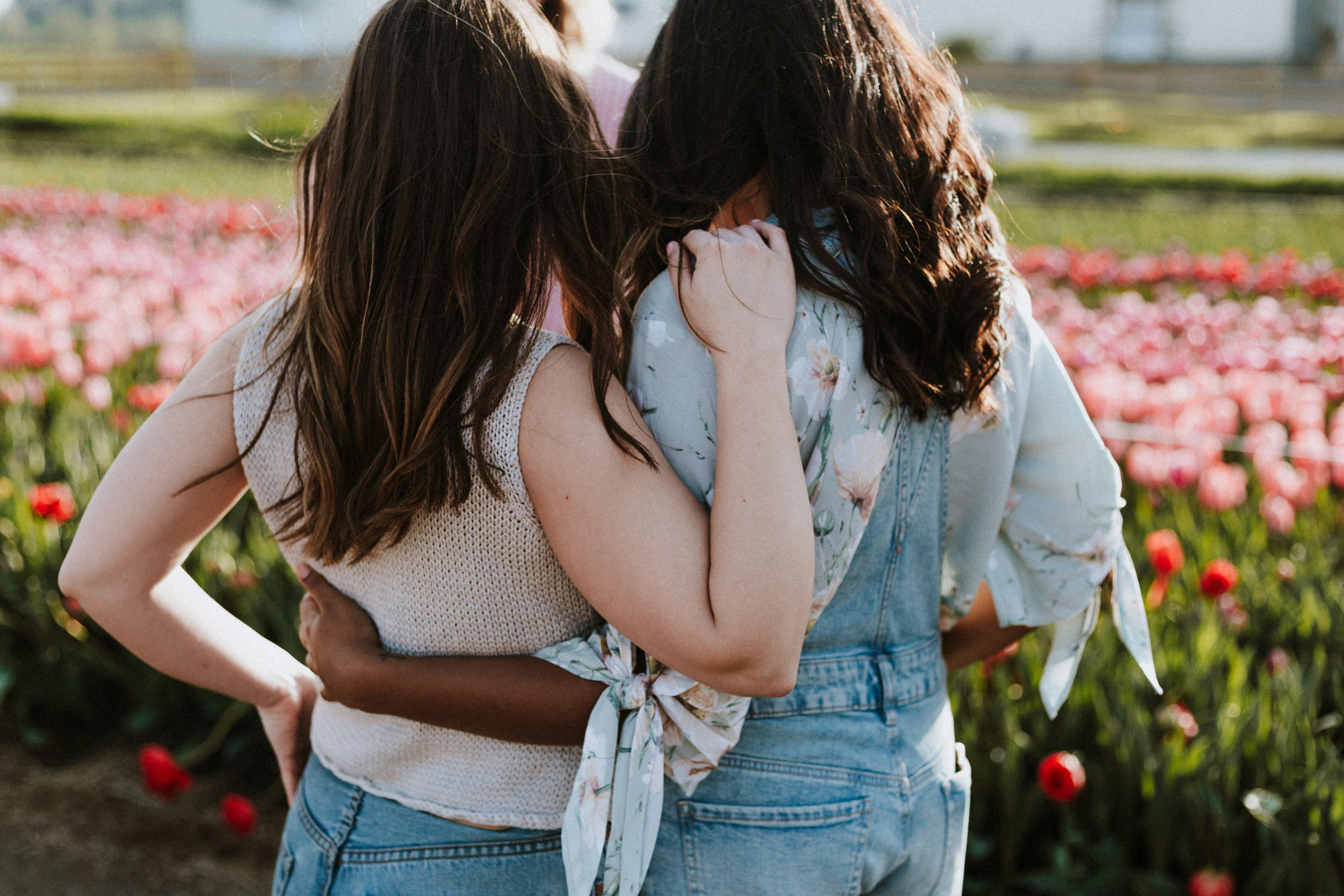 two women comforting each other facing a flower field.